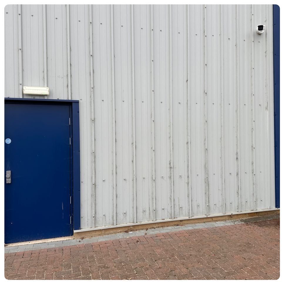 Industrial unit entrance with dirt-streaked white cladding