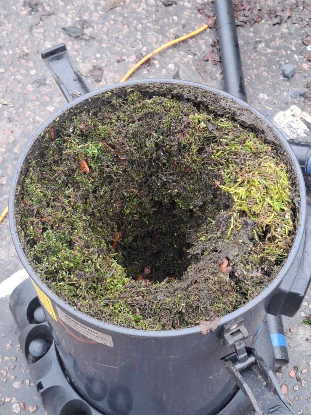 Vacuum drum filled with moss and debris removed from a commercial gutter system